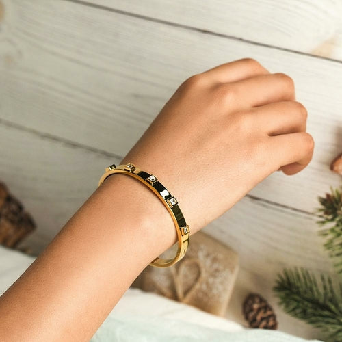 Gold bracelet on a wrist with a neutral background